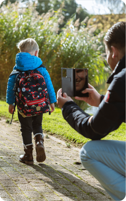 Een ouder fotografeert een kind dat zijn rugzak gebruikt