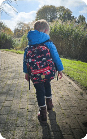 Het kind draagt dezelfde rugzak buiten